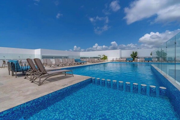 Ein Pool auf dem Dach mit Liegestühlen und blauem Himmel.
