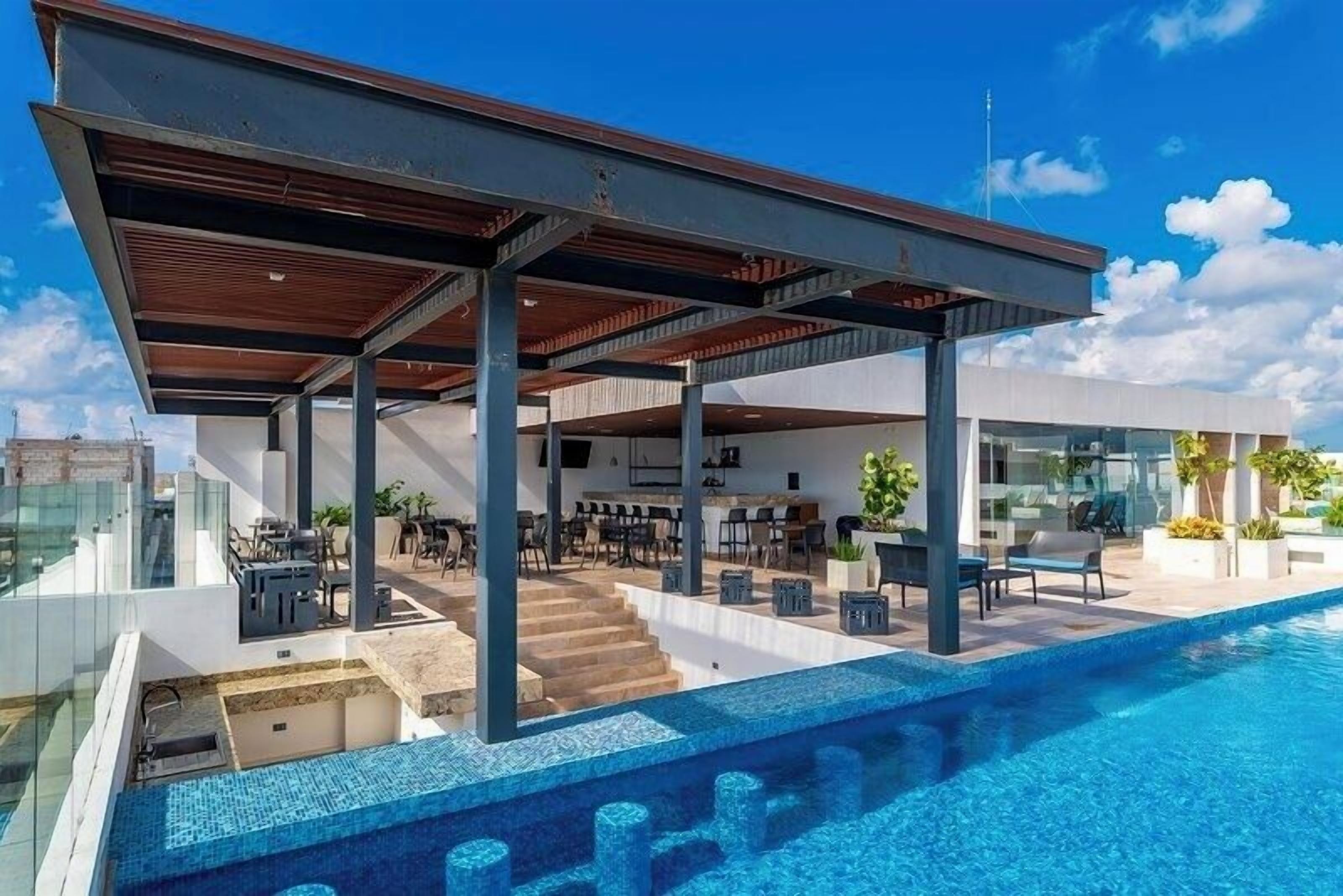 Een modern huis met een zwembad, buitenmeubilair en een overdekt terras.