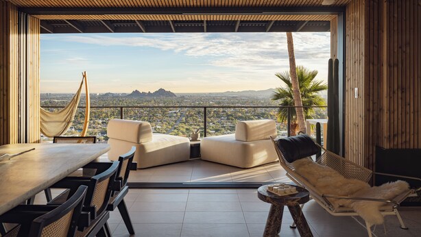 Un área de estar moderna al aire libre con vista panorámica de la ciudad, una hamaca y una planta de cactus.