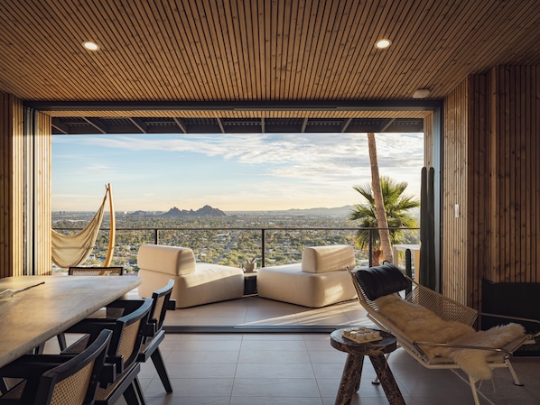 A modern outdoor seating area with a panoramic city view, a hammock, and a cactus plant.