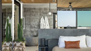 Un dormitorio moderno con una cama grande, un ventilador de techo y una pared de piedra.
