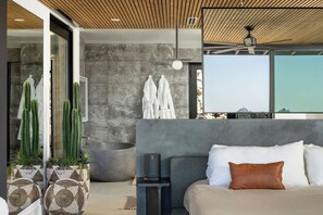 A modern bedroom with a large bed, a ceiling fan, and a stone wall.