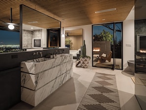A modern bathroom with a large marble sink, a freestanding bathtub, and a glass-enclosed shower area.