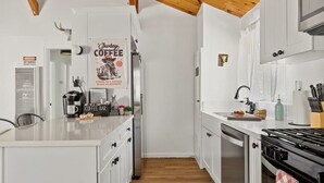 Een moderne keuken met witte kasten, een koffiebar en een bord met de tekst 'Cowboy Coffee'.