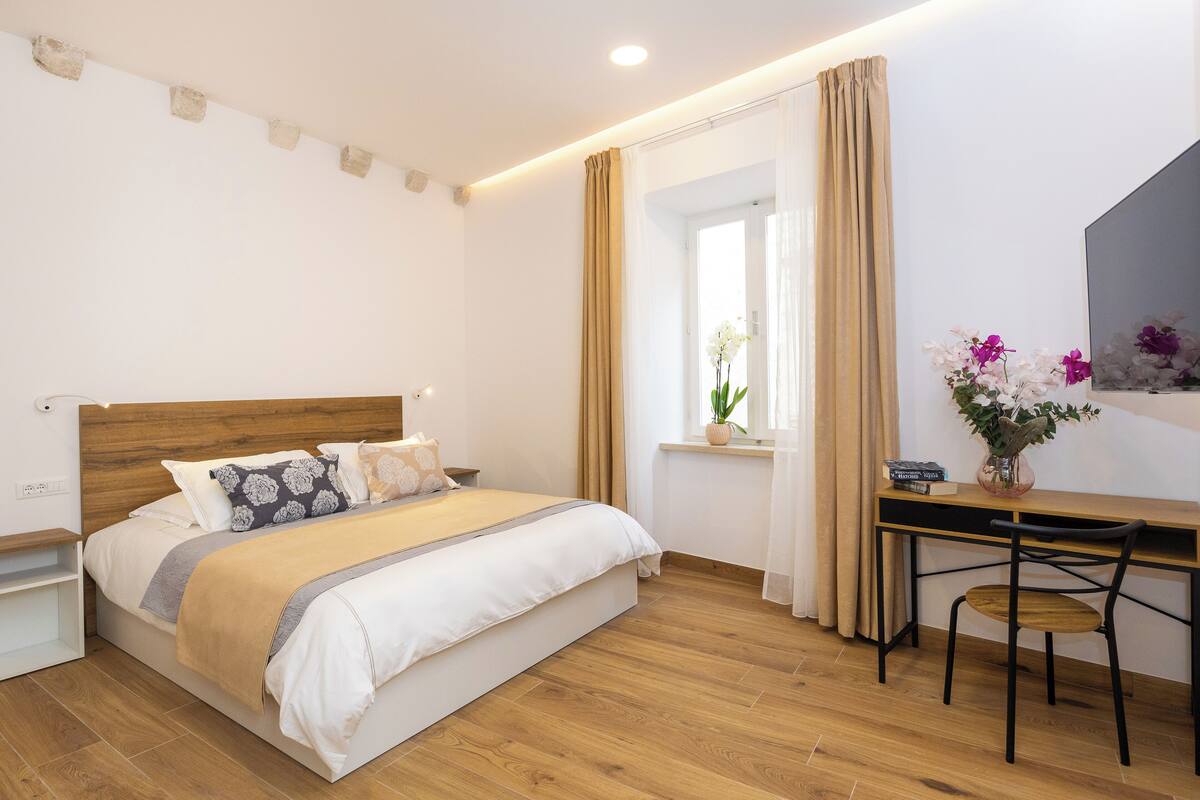 A bedroom with a wooden bed, a desk, and a chair.