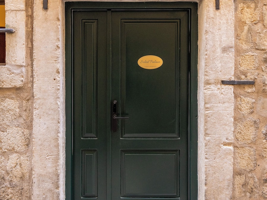 A dark green door with a plaque reading "Soleil Palace."