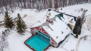 A snow-covered building with a swimming pool, surrounded by trees.