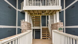 A wooden staircase leading to a balcony with a stone wall on either side.