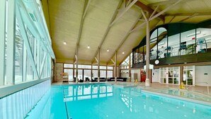 An indoor swimming pool with clear water, surrounded by a high ceiling and large windows. - Hideaway 2BR Condo Pool & Heated Pool (Shanty Bay)