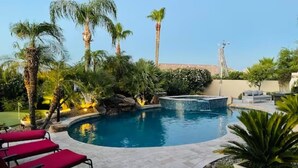 A swimming pool with a waterfall feature, surrounded by palm trees and a stone patio. - Luxury Contemporary Sanctuary w/  Pool and Views! (Fountain Hills)