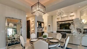 A modern dining area with a round table, white chairs, and a chandelier. - Luxury Contemporary Sanctuary w/  Pool and Views! (Fountain Hills)