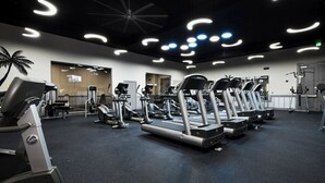 Un gimnasio con cintas de correr, elípticas y máquinas de pesas.