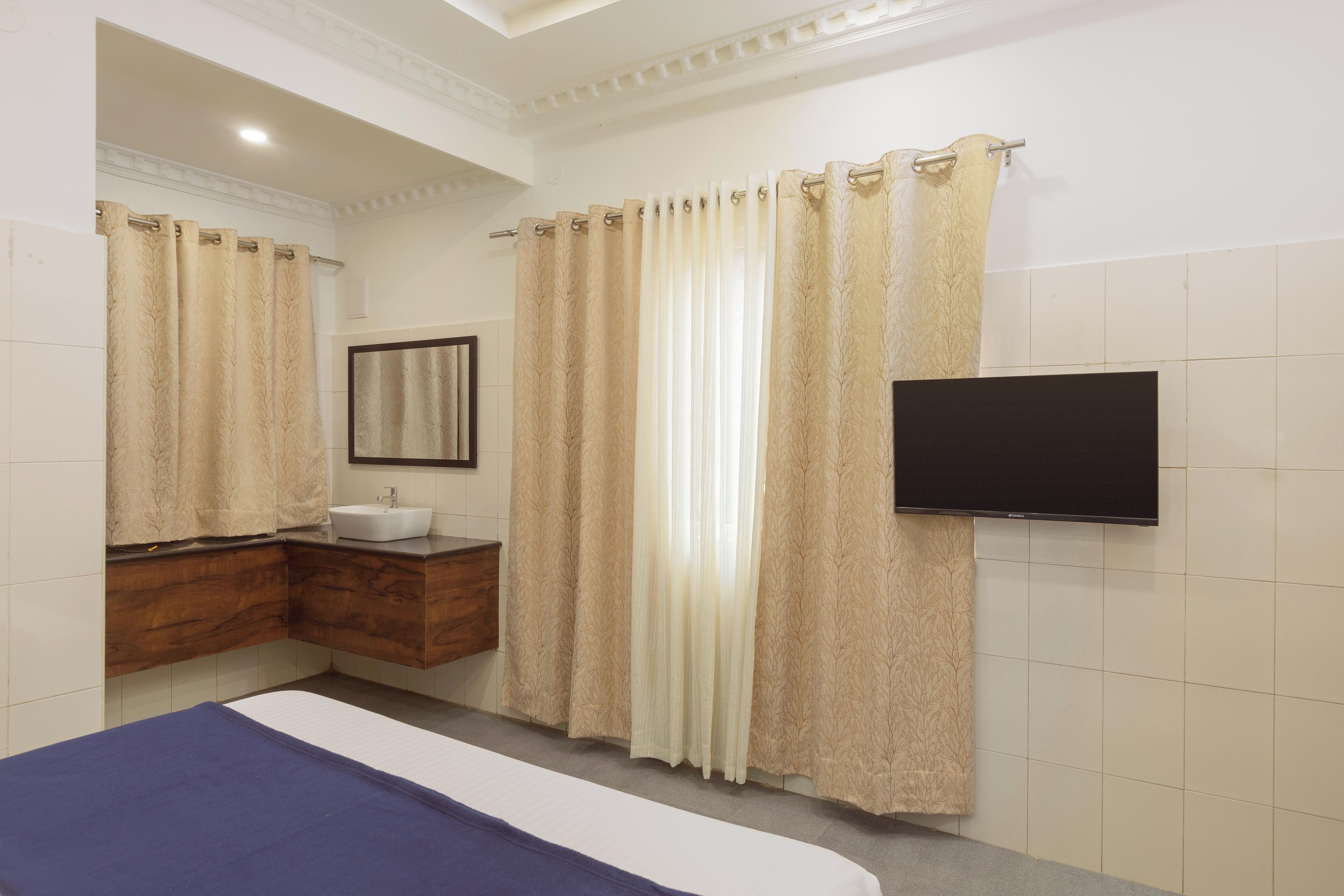 A hotel bathroom with a bed, a sink, a mirror, and a TV.