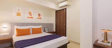 Un dormitorio con cama, mesitas de noche, ventilador de techo, aire acondicionado instalado en la pared y cuadros enmarcados.