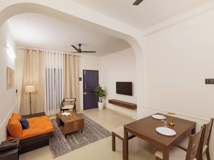 A modern living room with a sofa, coffee table, dining table, and TV.