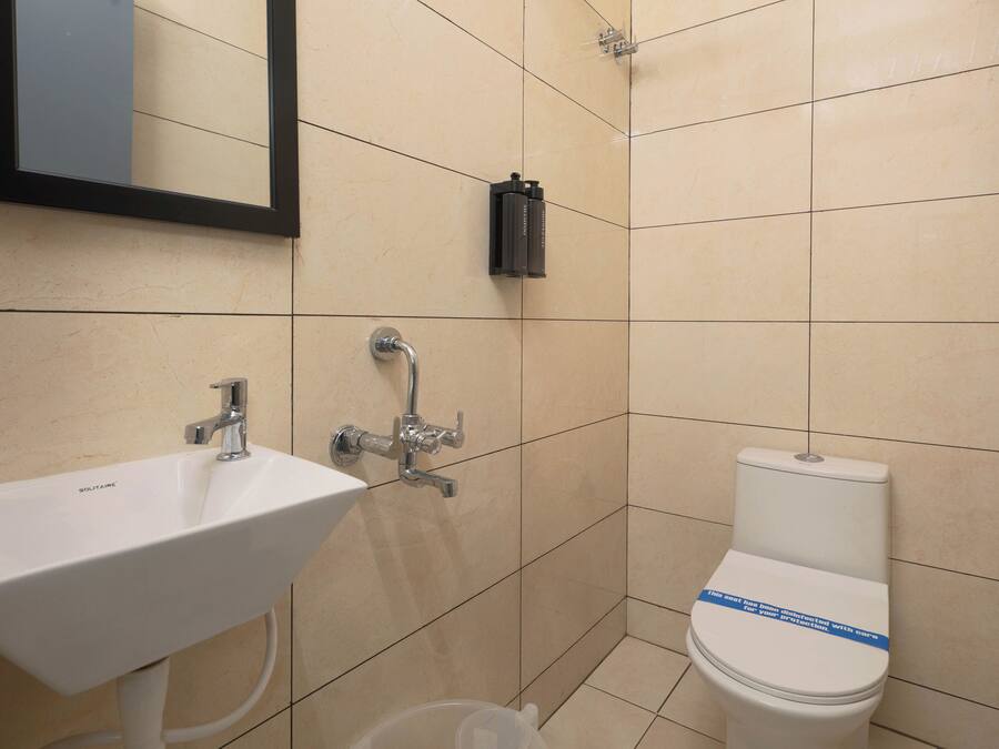 Une salle de bain avec un lavabo blanc, un miroir et des toilettes.