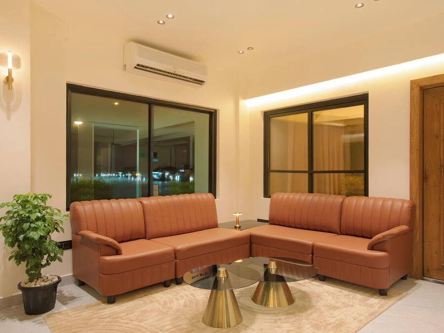 A modern living room with a sectional sofa, a glass coffee table, and a potted plant.