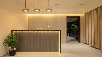 A reception area with a modern design, featuring a reception desk, potted plants, and a view into the interior.