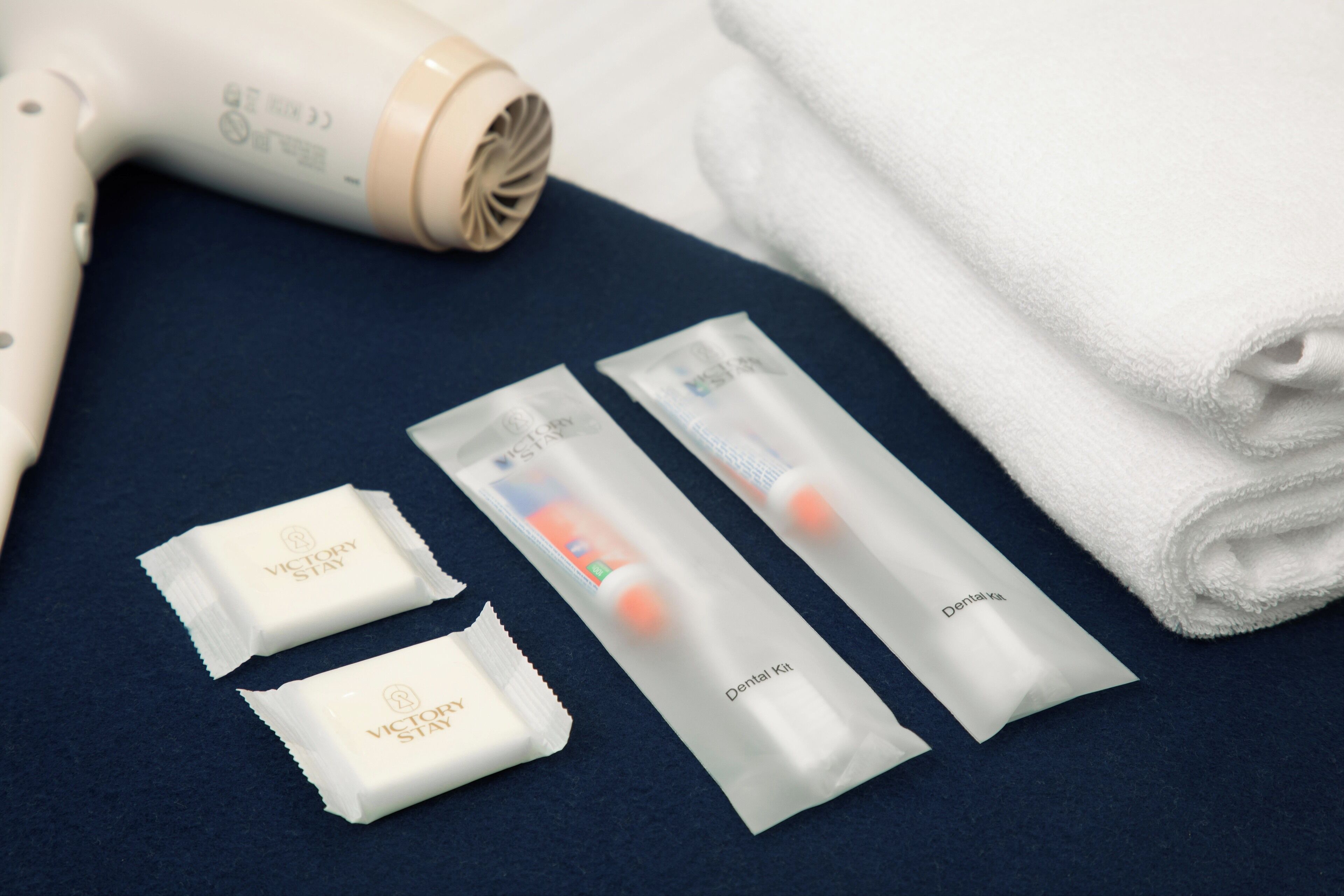 A dental care kit, a hair dryer, and a folded white towel on a dark surface.