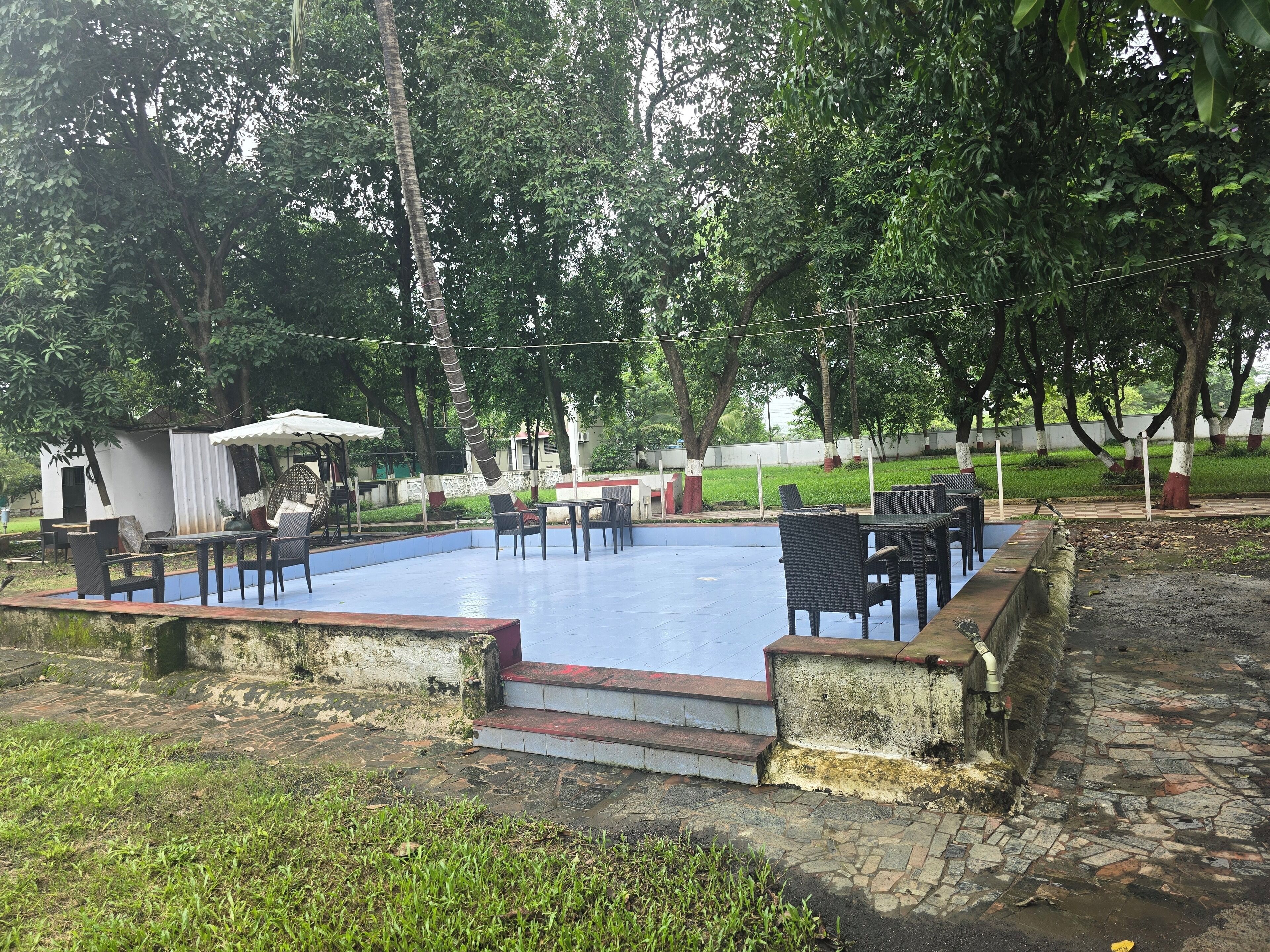 Un espace extérieur avec une piscine, des sièges et un petit pavillon.