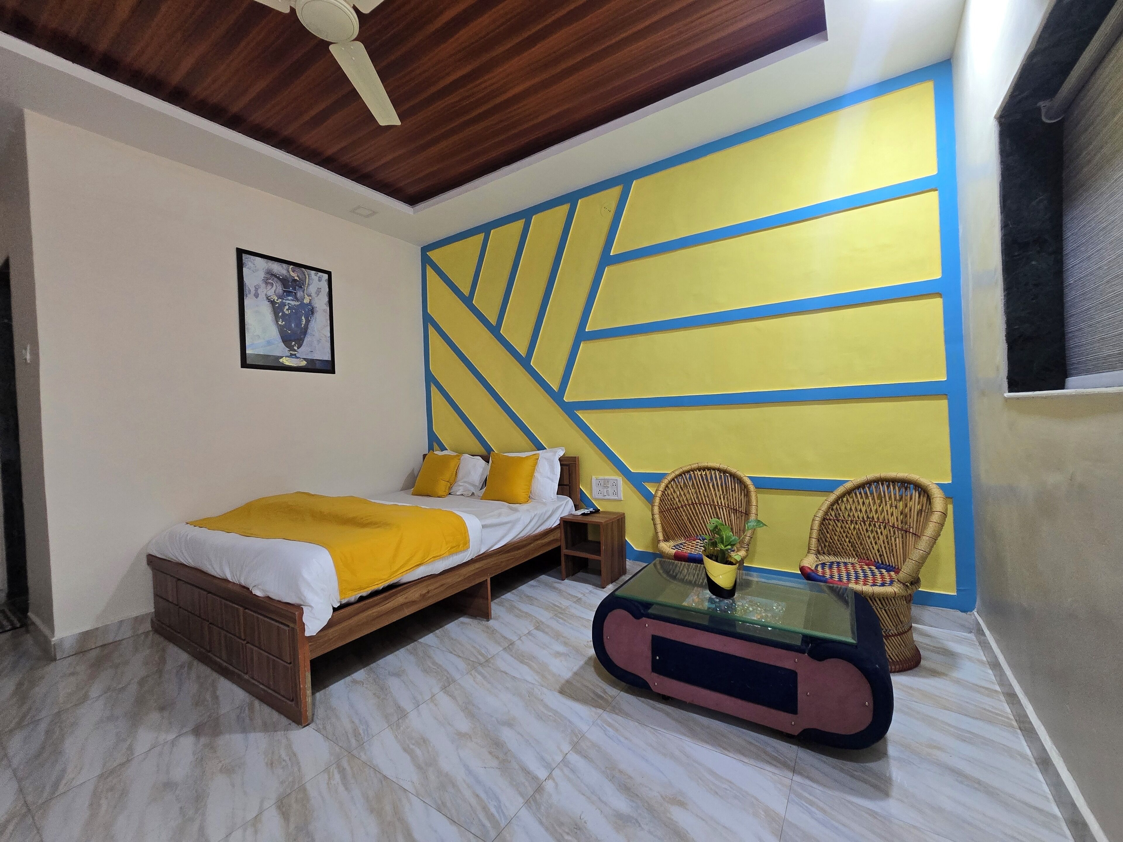 Ein Schlafzimmer mit einem Bett, zwei Korbstühlen, einem Glastisch und einem Deckenventilator.