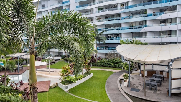 A modern hotel with multiple balconies, a central courtyard with a pool, and outdoor seating areas. - WaterEdge West End Retreat (West End)