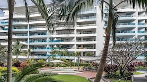 A multi-story hotel with balconies, a swimming pool, and tropical landscaping. - WaterEdge West End Retreat (West End)