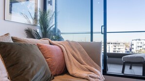 A balcony with a sofa, a blanket, and a view of buildings. - Wellness and Style - 2BR Apartment with Pool, Hot Tub and Gym (Moonee Ponds)