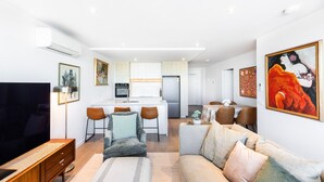 A modern apartment with a living room, dining area, kitchen, and a small balcony. - Wellness and Style - 2BR Apartment with Pool, Hot Tub and Gym (Moonee Ponds)