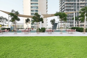 A modern outdoor area with seating arrangements and greenery, surrounded by high-rise buildings.