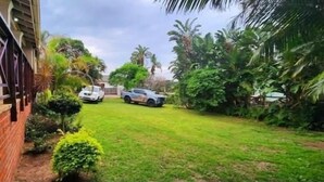 A residential property with a well-maintained lawn, a brick wall, and a car parked in the driveway. - Shelly Beach lodg  (Margate)
