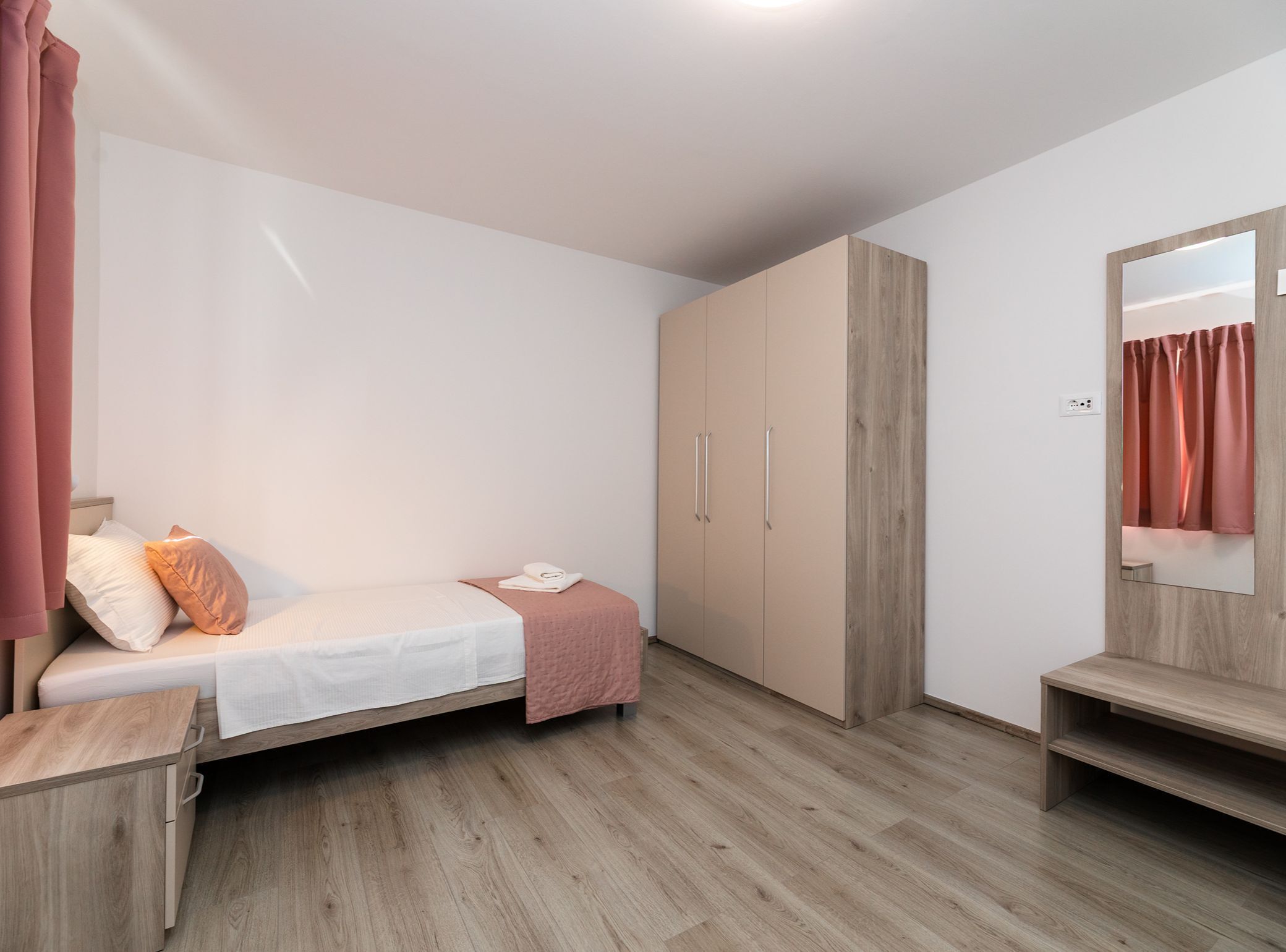 A bedroom with a bed, a wardrobe, a mirror, and a bench.
