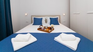 A hotel room with a bed, two pillows, a tray with breakfast items, and two towels on the bed. - Apartment Kurte (Nerezise)