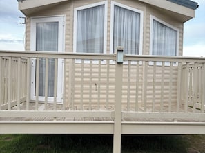 A two-story building with a balcony, a door, and a window with curtains. - Caravan 607 (Clacton-on-Sea)