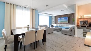 A modern living room with a dining area, a kitchen, and a TV mounted on the wall. - 2817 Storey Lake Kissimmee (Kissimmee)