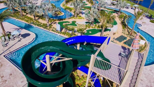 A water park with a large green water slide, multiple pools, and palm trees. - 2817 Storey Lake Kissimmee (Kissimmee)
