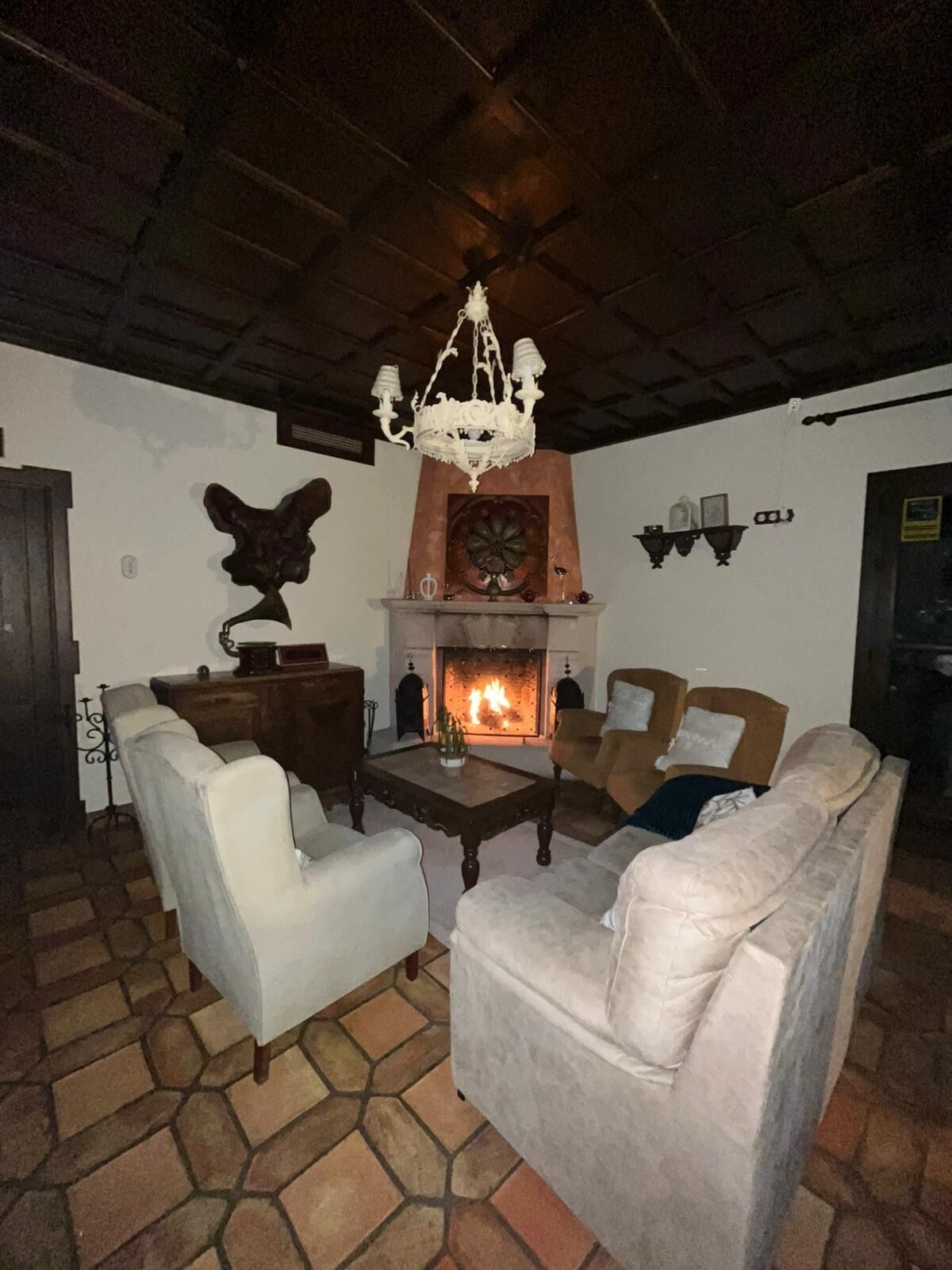 Una sala acogedora con chimenea, muebles blancos y una araña.