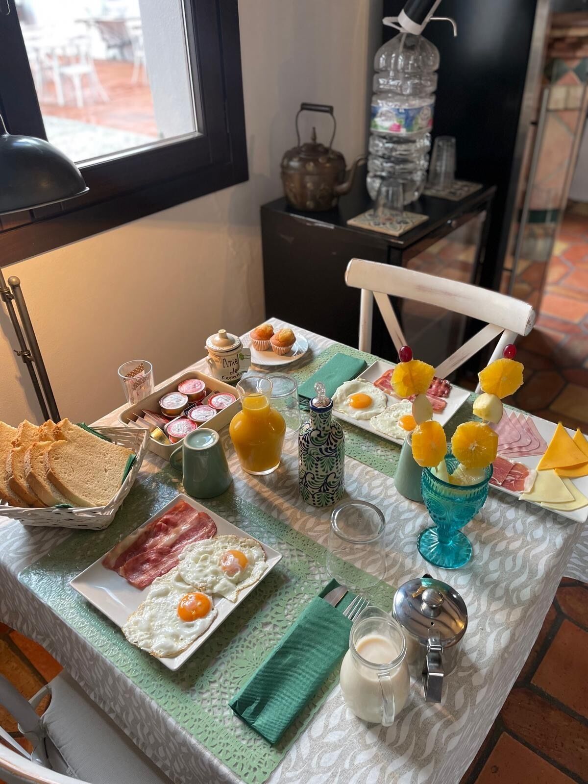 Una mesa de desayuno con diversos alimentos, como huevos, pan y bollería.