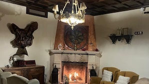 A cozy living room with a fireplace, a chandelier, and classic furniture. - Hotel Rural La Hacienda de Ronda  (Ronda)