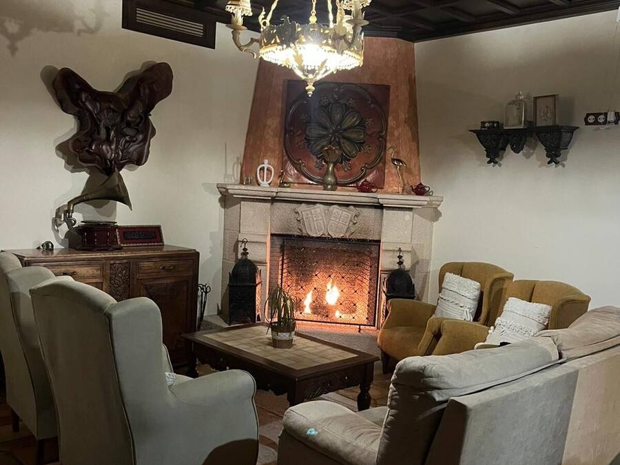 Una sala de estar acogedora con chimenea, asientos cómodos y un techo decorativo.