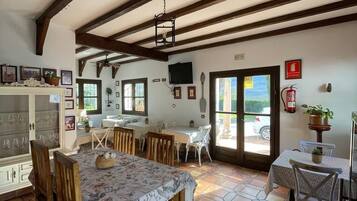 A dining area with a large table, chairs, and a ceiling with exposed beams.