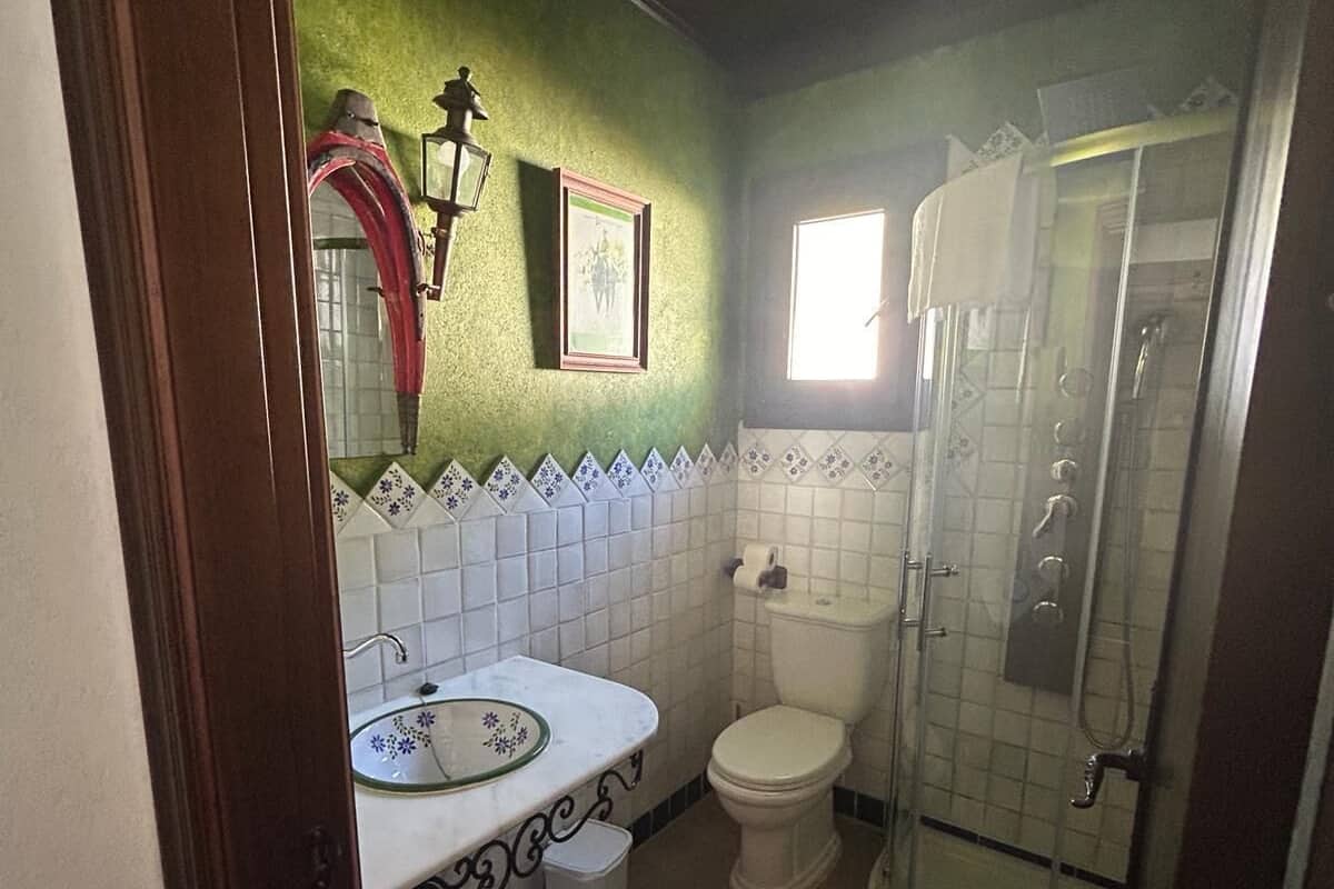 Ein Badezimmer mit weißem Waschbecken, Toilette und Duschkabine aus Glas.