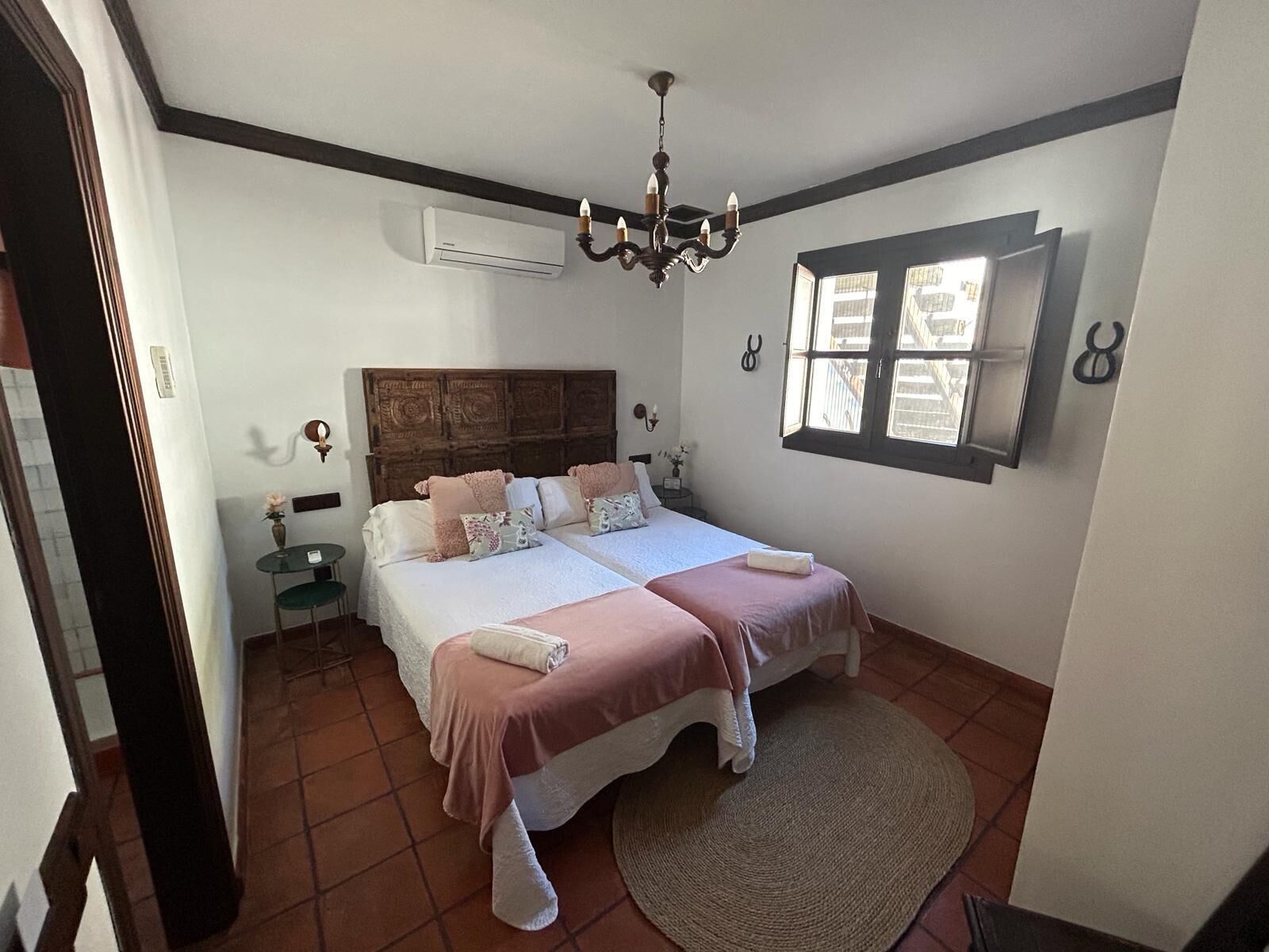 Une chambre à coucher avec un grand lit, un lustre, un appareil de climatisation et une fenêtre donnant sur un beau paysage.