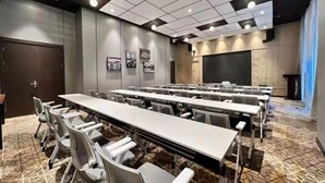 A conference room with multiple tables and chairs, a large screen, and a patterned carpet. - Jinjiang Metropolo Hotel Wuhan Sports Center Subway Station Wanda Plaza (Wuhan)