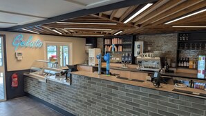 A modern gelato shop with a brick counter, a neon sign, and a coffee machine. - Nature's Nook - Billing Aquadrome (Northampton)