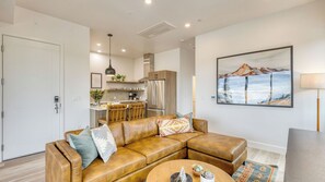 A modern living room with a leather sectional sofa, a round coffee table, and a kitchen in the background. - 2 Units Minutes to Old Bend, Deck + Hot Tub 1204 Skyline Ranch by Avantstay (Bend)