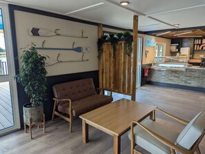A modern interior with a wooden table and chairs, a potted plant, and a wall with decorative paddles. - Nature's Nook - Billing Aquadrome (Northampton)