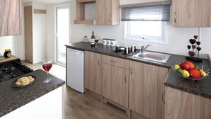 Een moderne keuken met houten kastjes, een ingebouwde vaatwasser en een fruitschaal op het aanrecht.