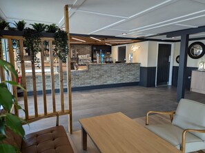 Ein modernes Interieur mit einer Rezeption, einer Sitzecke und einer Bar.