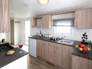 Eine moderne Küche mit Holzschränken, einem eingebauten Geschirrspüler und einer Obstschale auf der Arbeitsplatte.